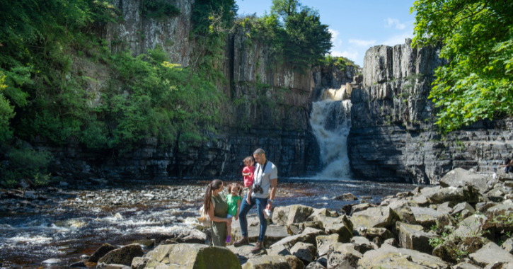 Family stood in front of High Force Waterfall.